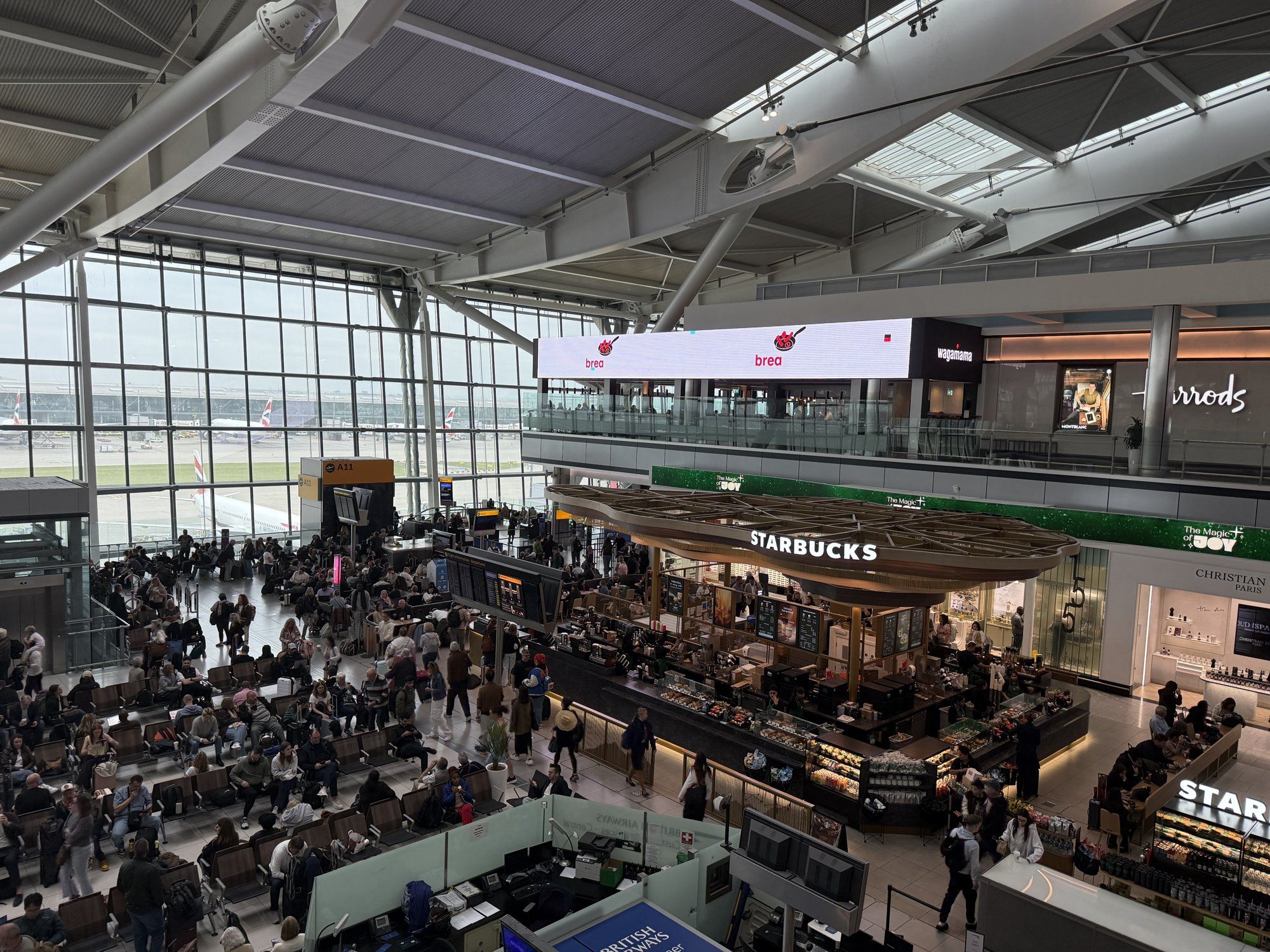 The departures hall at Heathrow Terminal 5, with shops and British Airways aircraft beyond the glass wall.