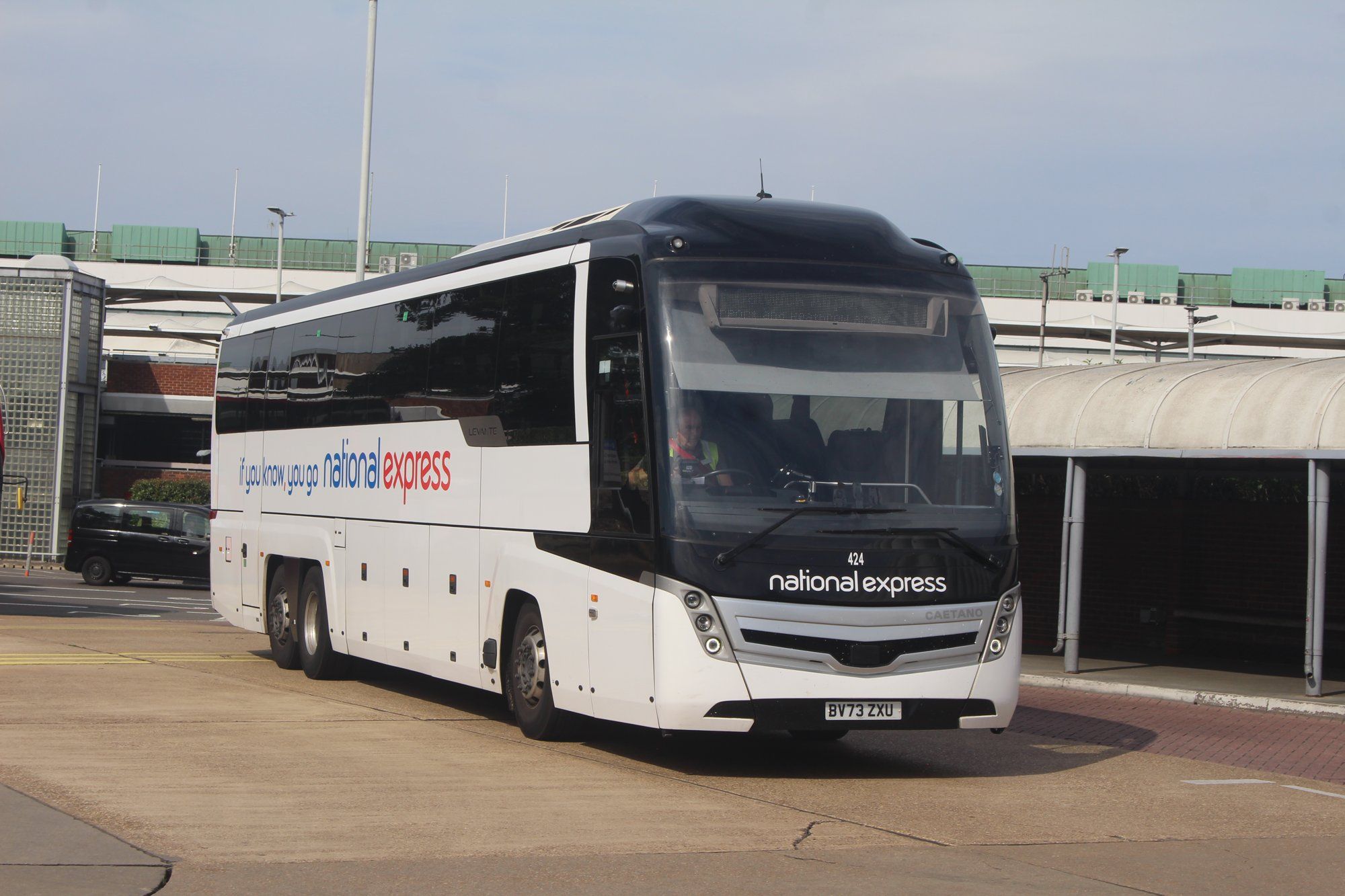 A National Express coach at the Heathrow Central Bus Station, with the terminal building behind.